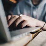 Hands typing a book proposal on a laptop